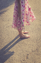 Mädchen steht barfuß auf der Straße und hält eine Blume - SARF000752