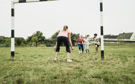 Vier Mädchen im Teenageralter spielen Fußball auf einem Bolzplatz - UUF001554