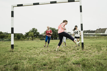 Vier Mädchen im Teenageralter spielen Fußball auf einem Bolzplatz - UUF001555