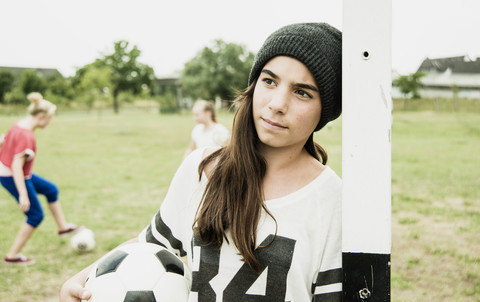 Teenage girl with soccer ball leaning at goalpost stock photo