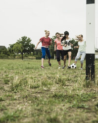 Vier Mädchen im Teenageralter spielen Fußball auf einem Bolzplatz - UUF001565