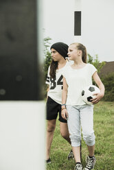 Two teenage girls with soccer ball standing on a football ground - UUF001588