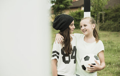 Two happy teenage girls standing on a football ground - UUF001567