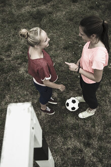 Zwei Mädchen im Teenageralter kommunizieren auf einem Fußballplatz, Blick von oben - UUF001573