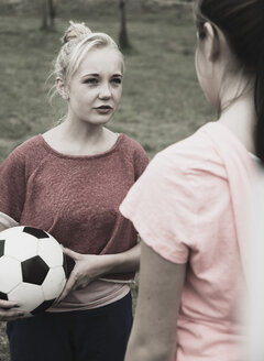 Zwei Mädchen im Teenageralter kommunizieren auf einem Fußballplatz, Teilansicht - UUF001574