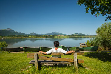 Deutschland, Bayern, Allgäu, Ostallgäu, Hopfensee, bei Füssen, Reife Frau sitzt auf Holzbank - WGF000410