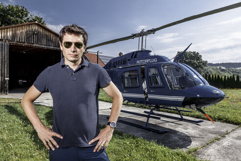 Germany, Bavaria, Landshut, Helicopter pilot standing with hands on hips - KDF000035