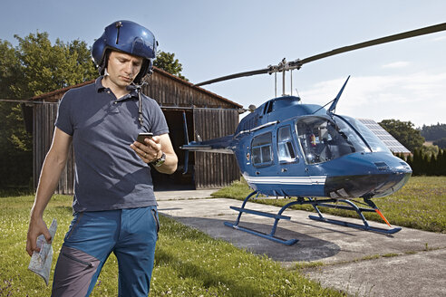 Germany, Bavaria, Landshut, Helicopter pilot using mobile phone - KDF000064