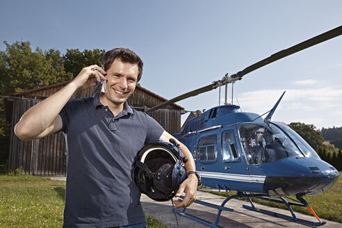Germany, Bavaria, Landshut, Helicopter pilot using mobile phone - KDF000065