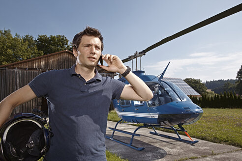 Germany, Bavaria, Landshut, Helicopter pilot using mobile phone - KDF000067