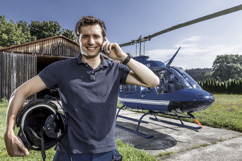 Deutschland, Bayern, Landshut, Hubschrauberpilot mit Mobiltelefon - KDF000078