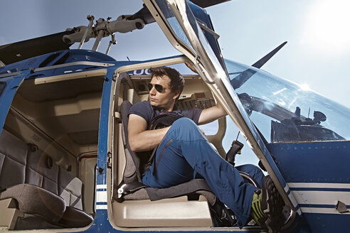Germany, Bavaria, Landshut, Helicopter pilot sitting in open helicopter, waiting - KDF000041