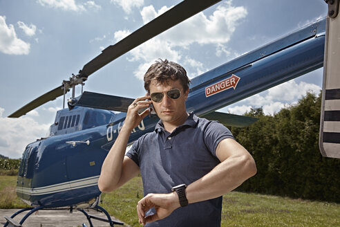 Germany, Bavaria, Landshut, Helicopter pilot using mobile phone - KDF000076