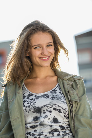 Porträt eines lächelnden Teenagers im Gegenlicht, lizenzfreies Stockfoto