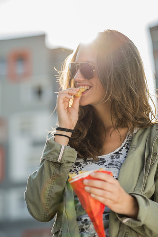 Porträt eines Teenagers mit Sonnenbrille, der Pommes frites isst, lizenzfreies Stockfoto