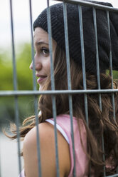 Profil eines lächelnden Teenagers hinter einem Zaun mit Wollmütze - UUF001605