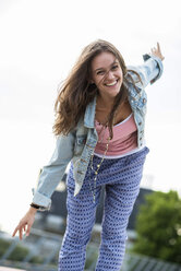 Porträt eines lächelnden Teenagers, der mit ausgestreckten Armen balanciert - UUF001611