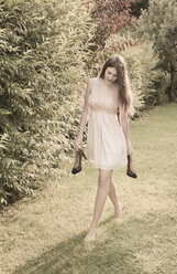 Junge Frau geht barfuß auf einer Wiese im Garten - FCF000406