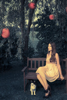 Porträt einer jungen Frau, die in der Dämmerung auf einer Gartenbank sitzt - FCF000438