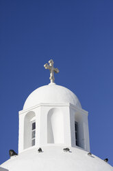 Griechenland, Kykladen, Santorin, Kuppel mit Kruzifix einer weißen Kirche vor blauem Himmel - KRPF000850