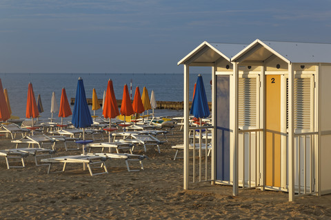 Italien, Friaul-Julisch Venetien, Provinz Udine, Strand mit Liegestühlen und Umkleidekabinen, lizenzfreies Stockfoto