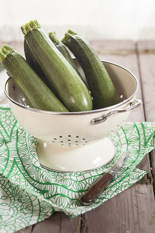 Zucchinisieb und ein Messer auf Tuch und Holz, lizenzfreies Stockfoto