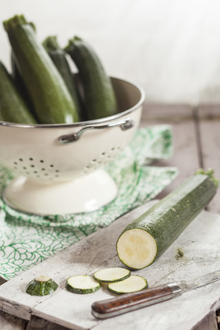 Zucchinisieb und ein Messer und Zucchinischeiben auf einem Schneidebrett, lizenzfreies Stockfoto