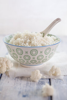 Bowl of cauliflower rice and cauliflower florets on cloth and wood - SBDF001226