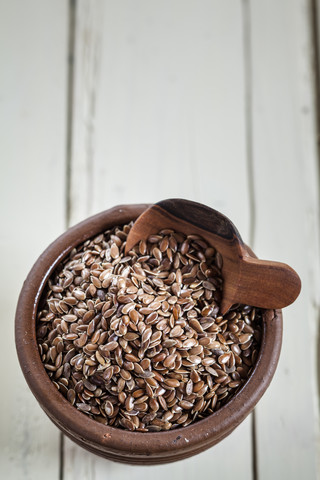 Schale aus Steingut mit Bio-Leinsamen, Linum usitatissimum, auf weißem Holz, lizenzfreies Stockfoto