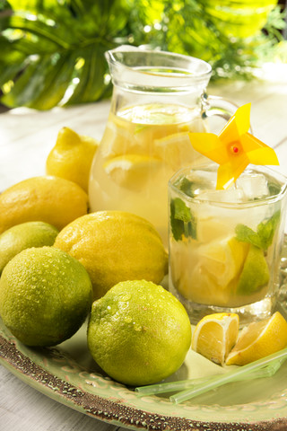 Carafe of home made lemonade splash and a drinking glass with slices of lemon stock photo