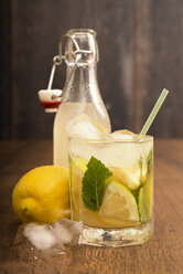 Glass of home made lemonade splash with slices of lemon and clip-top bottle - CSTF000371