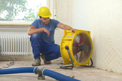 Worker controlling dehumidifier in an apartment which is damaged by flooding - LAF001026