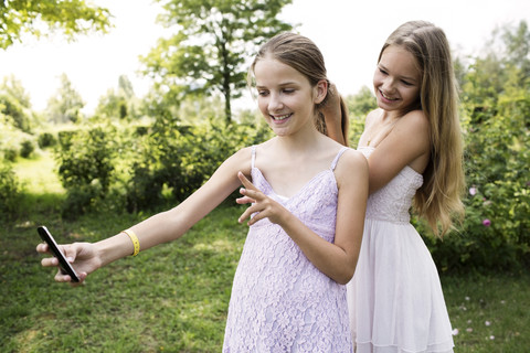 Girl taking a selfie while her sister brushing her hair stock photo