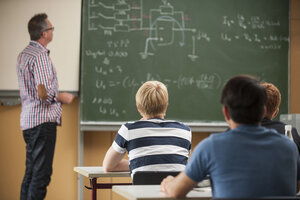 Berufsschüler im Klassenzimmer mit Lehrer an der Tafel - PAF000806