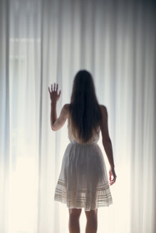 Mystische junge Frau vor einem weißen Vorhang stehend, Rückansicht - BRF000571