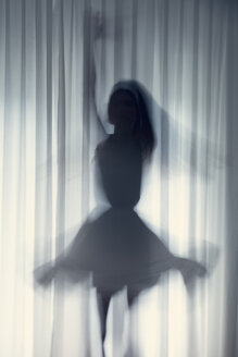Silhouette einer jungen Frau, die vor einem weißen Vorhang tanzt - BRF000570