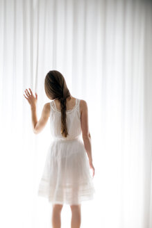 Young woman touching a white curtain, back view - BRF000572