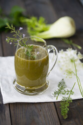 Glas Wildkräuter-Smoothie auf Stoff und dunklem Holz - MYF000523