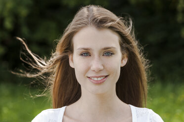 Porträt einer lächelnden jungen Frau mit wehendem Haar - TCF004096