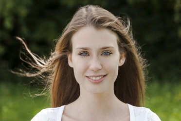 Portrait of smiling young woman with blowing hair - TCF004096