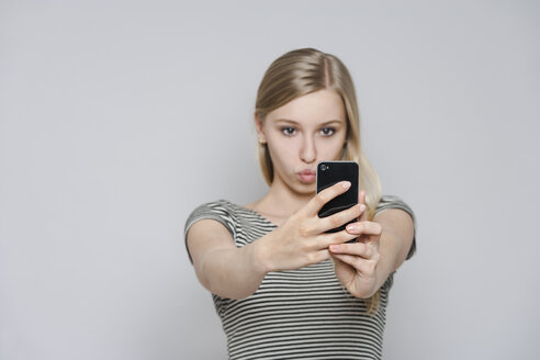 Porträt einer jungen Frau, die ein Selfie mit ihrem Smartphone macht - TCF004111