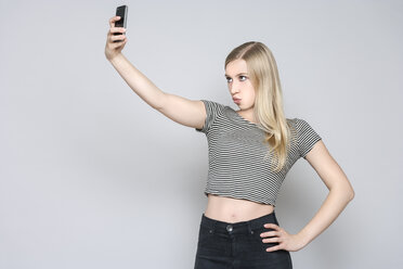 Porträt einer jungen Frau, die ein Selfie mit ihrem Smartphone macht - TCF004112