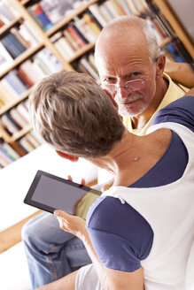Älteres Paar sitzt auf der Couch und benutzt ein digitales Tablet - JUNF000004