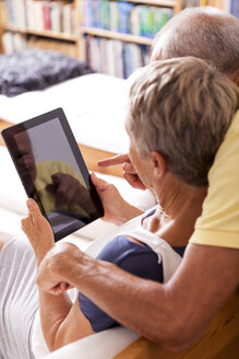 Senior couple sitting on couch using digital tablet, partial view - JUNF000006