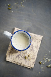 Tasse Sojareismilch mit Kardamom und Zimt auf Serviette und Holz, Blick von oben - MYF000527