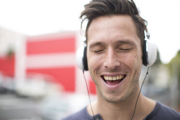 Portrait of singing young man listening music with headphones - ZEF000031