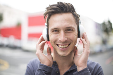 Portrait of smiling young man listening music with headphones - ZEF000032