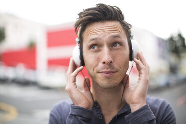 Porträt eines jungen Mannes, der mit Kopfhörern Musik hört - ZEF000013