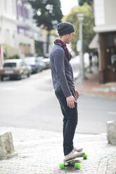 Young man standing on his skateboard on sidewalk - ZEF000041