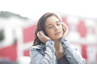 Portrait of young woman with closed eyes listening music with headphones - ZEF000065